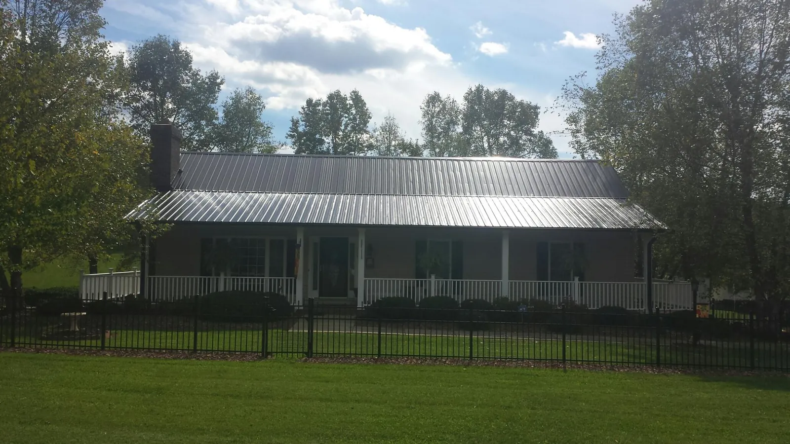 Gray metal roof on a brick ranch with a full width front porch — Gutter Guard Installation work by our crew in Staffordsville