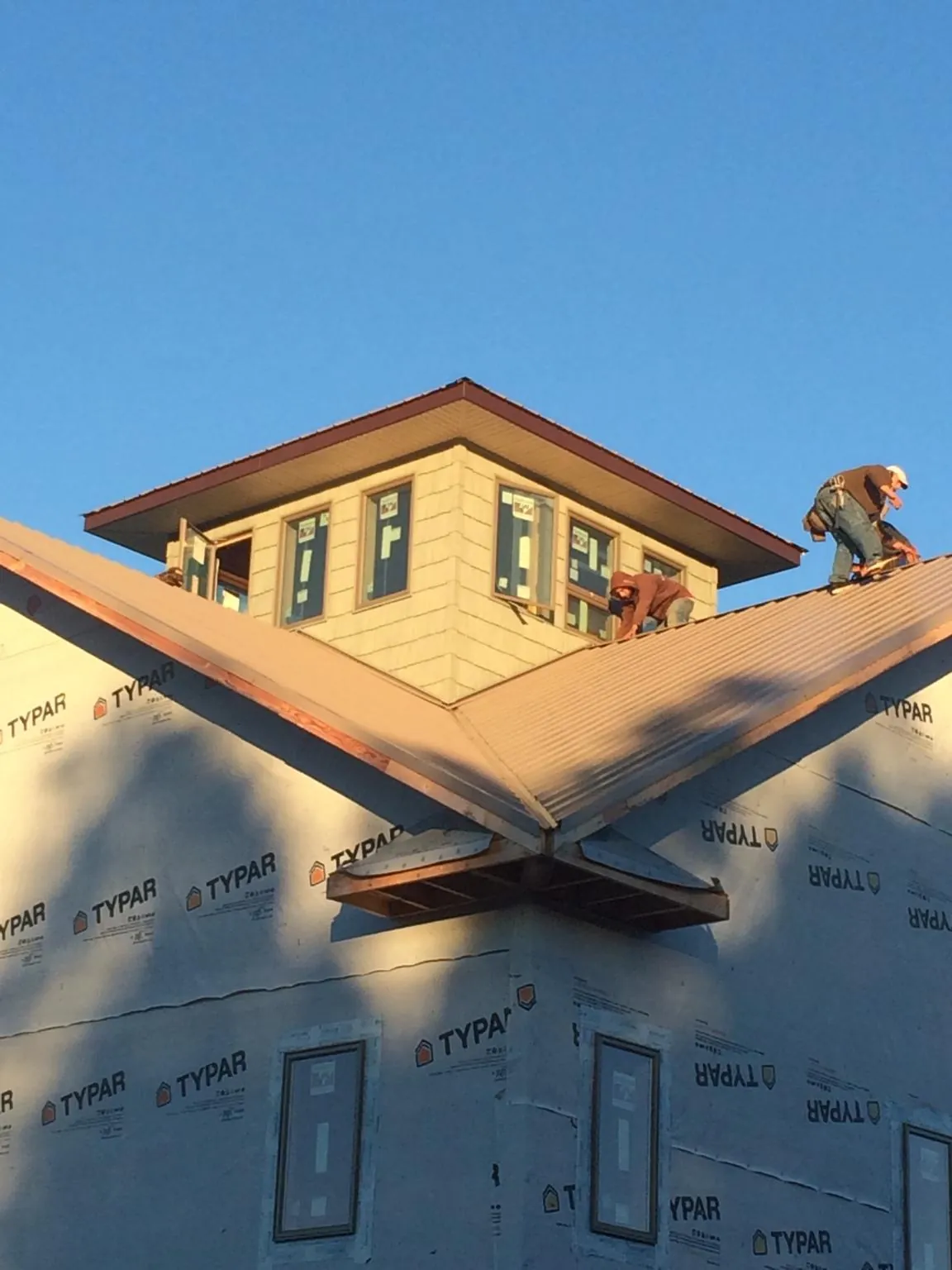 Roofers working around a rooftop cupola on a new metal roof at sunset — Roof Waterproofing in Staffordsville by Roofing Brothers
